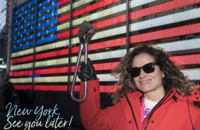 Emille holding the Subway Handle in front of the American Flag in Times Square, NYC